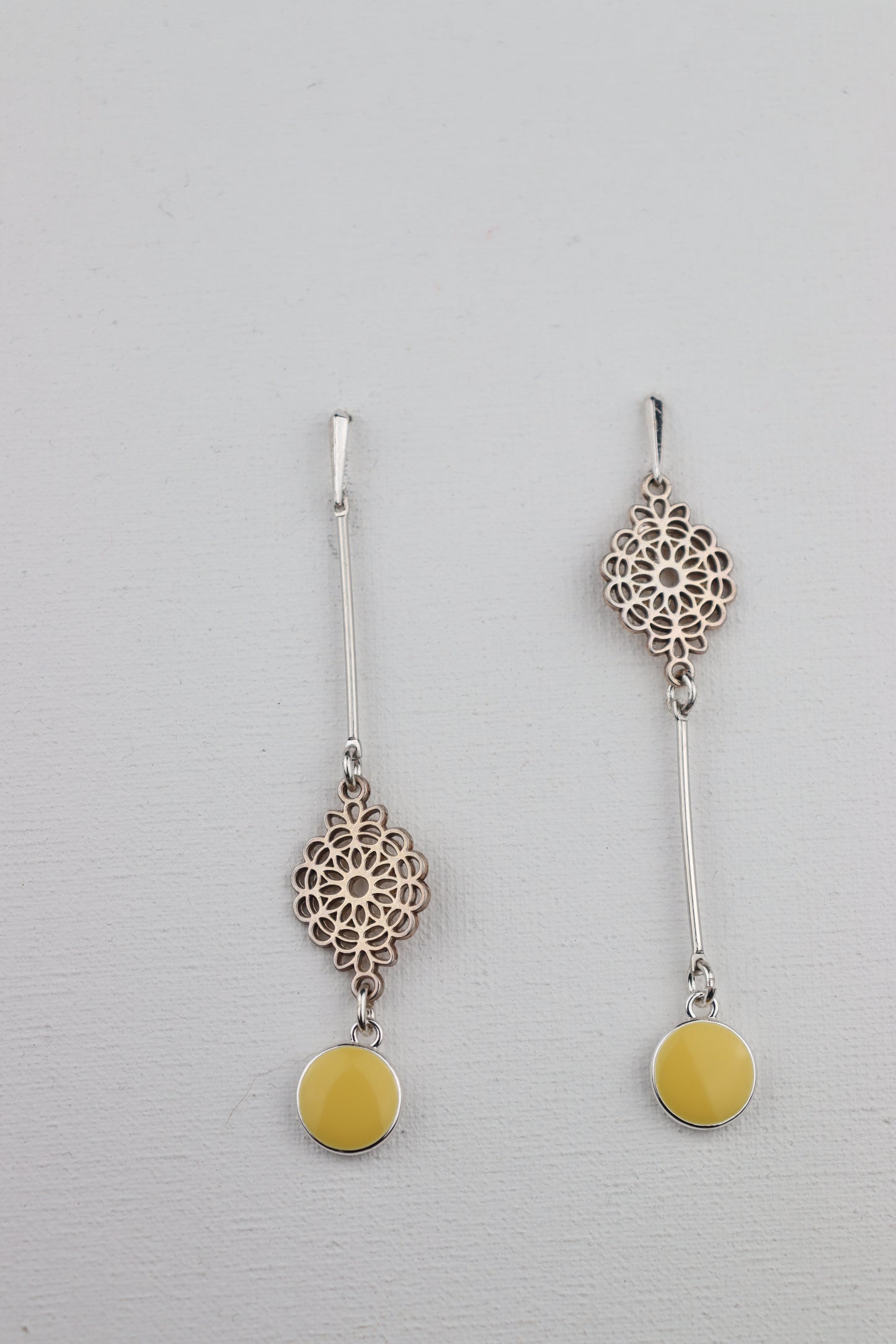 Asymmetrische zilverkleurige oorhaken met gele hangers