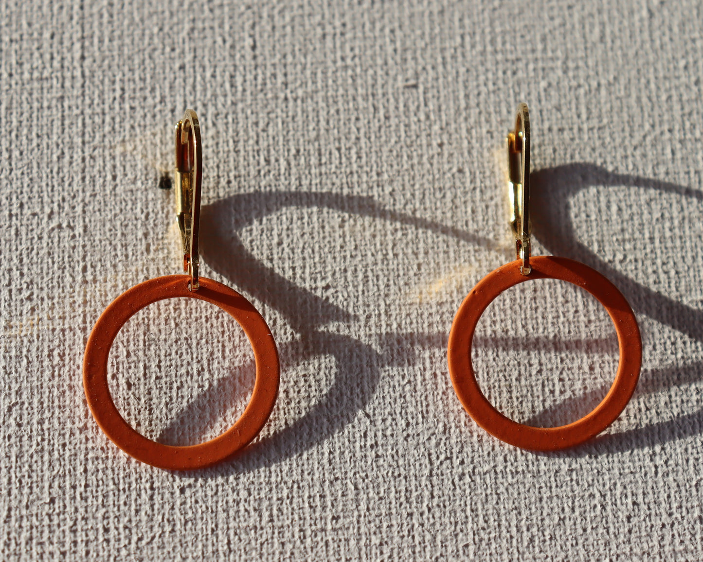 Goudkleurige oorbellen met oranje berubberde cirkel