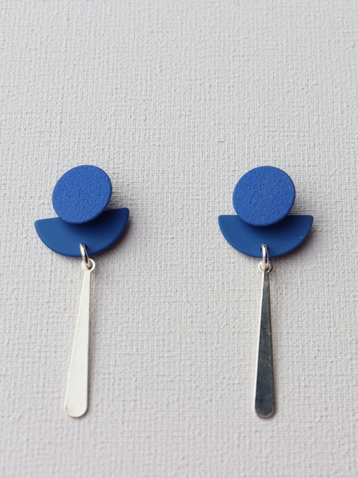 Blauwe ronde oorstekers met blauwe halve cirkel en zilverkleurige druppel