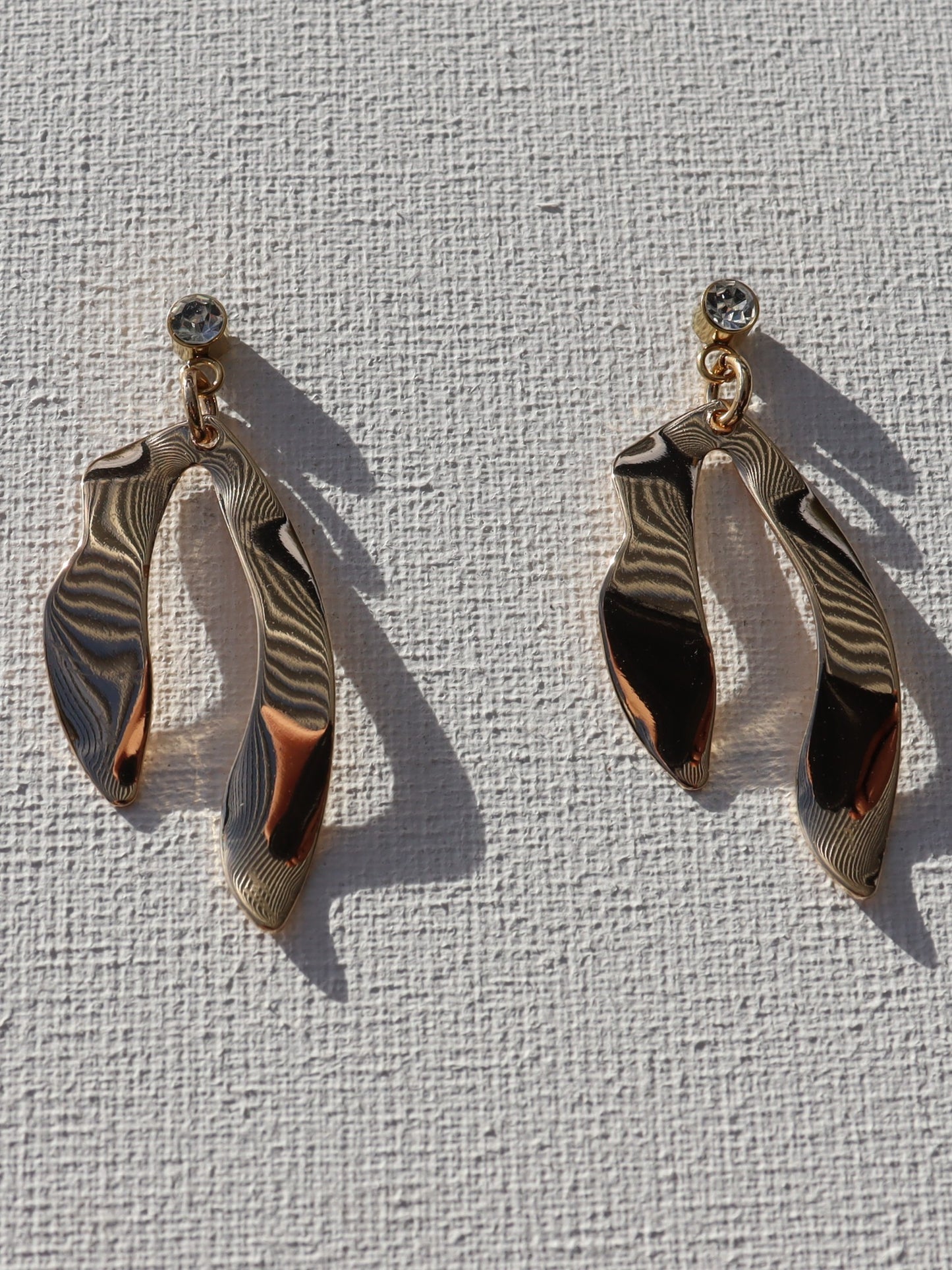 Goudkleurige steenstekertjes met goudkleurige kronkelhanger