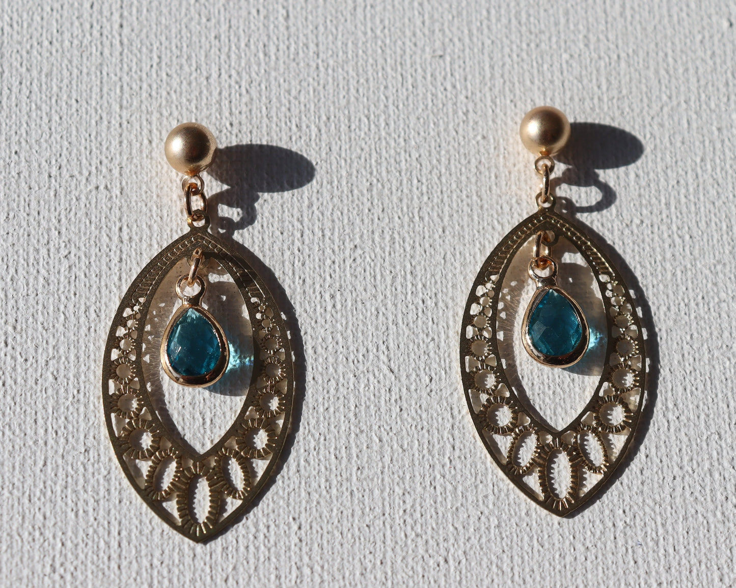 Goudkleurige knopstekertjes met goudkleurige boho hanger en blauwe steen