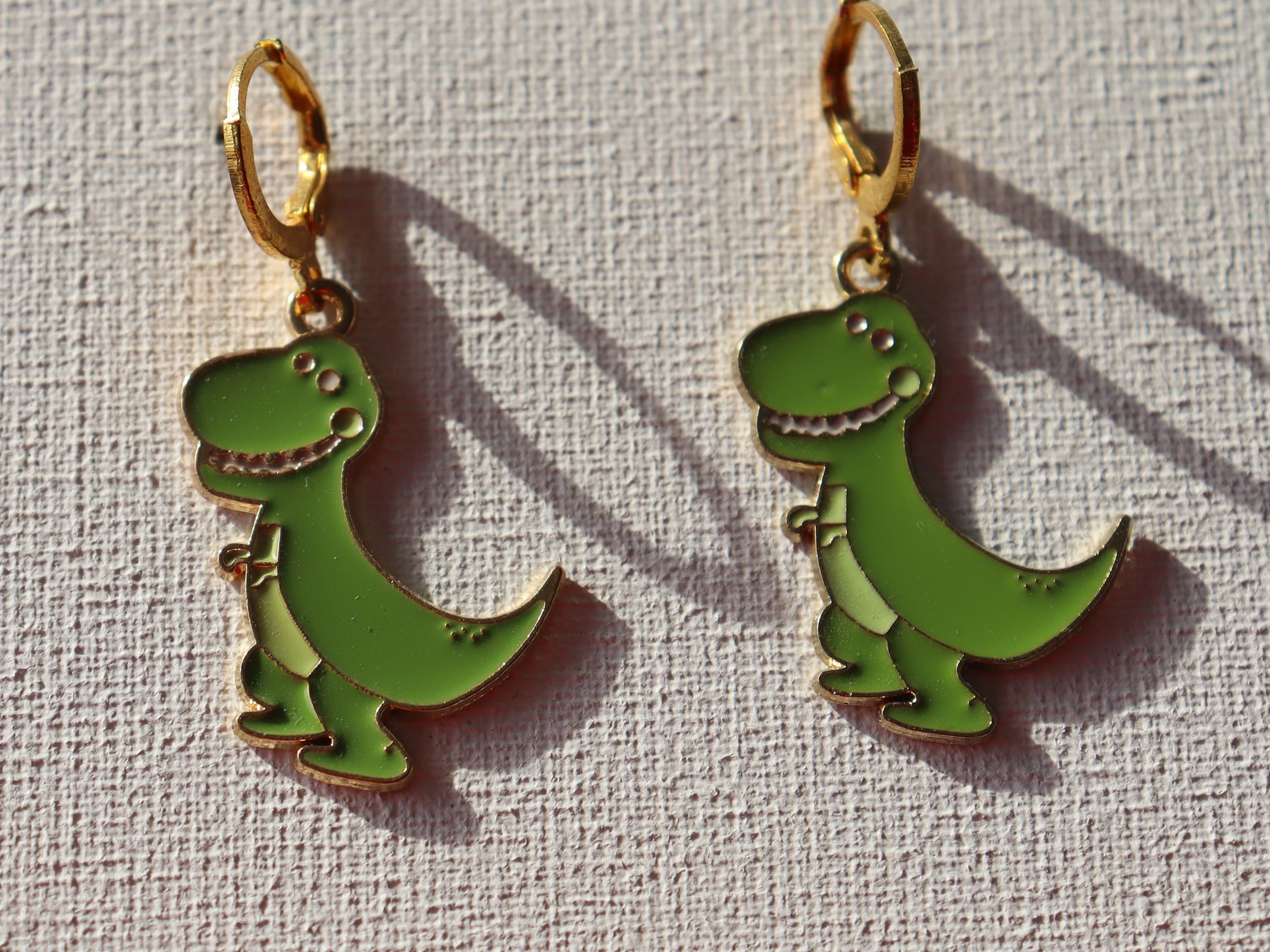 Goudkleurige oorbelringen met groene dino