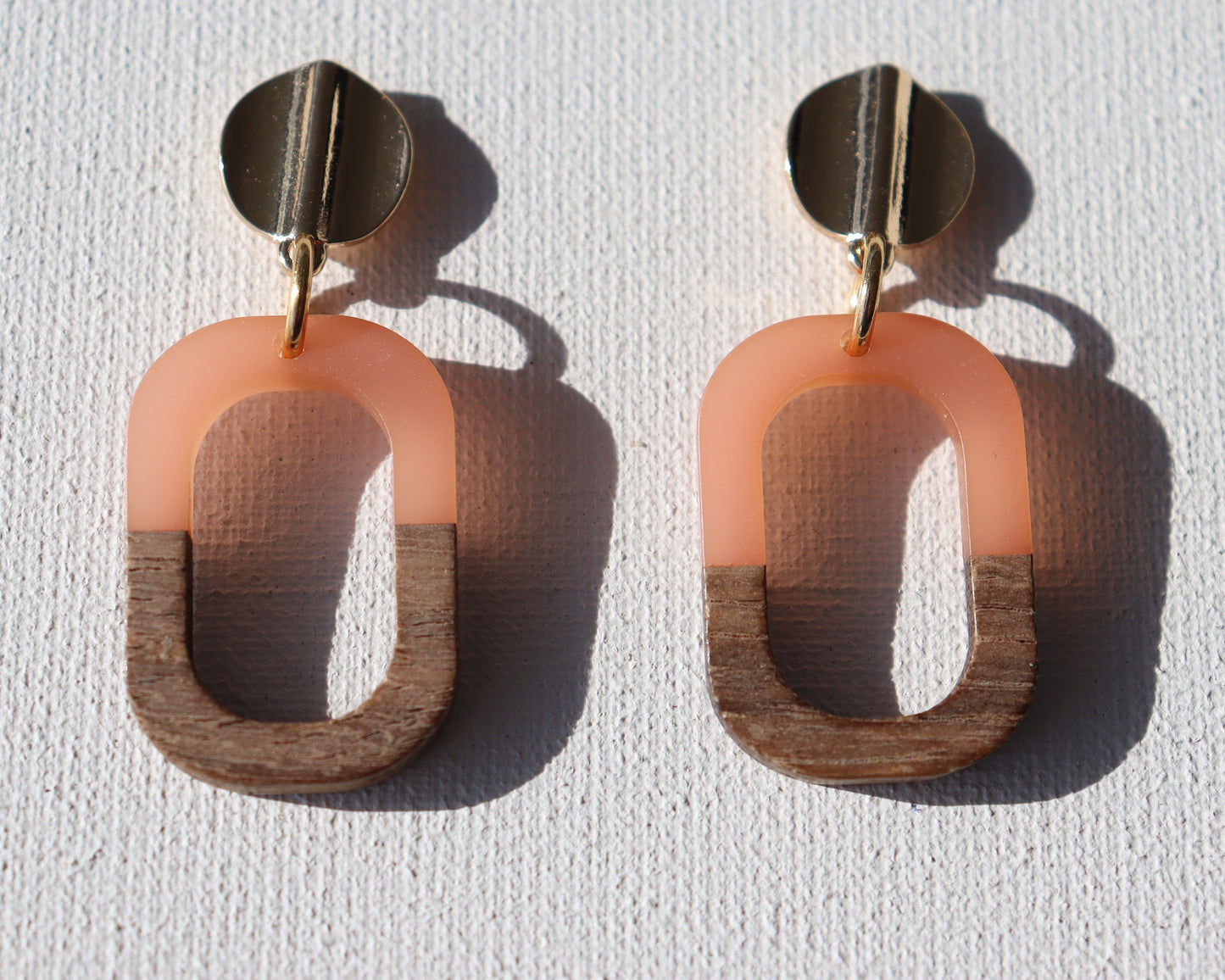 Goudkleurigerondegolfstekertjesmethoutenopenrechthoekmet zalmroze kunsthars