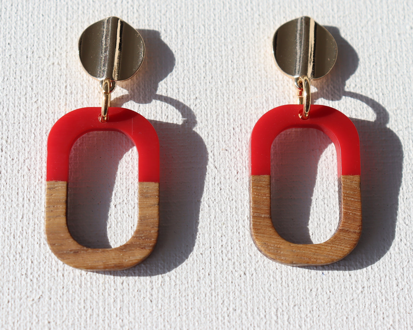 Goudkleurigerondegolfstekertjesmethoutenopenrechthoekmet rode kunsthars