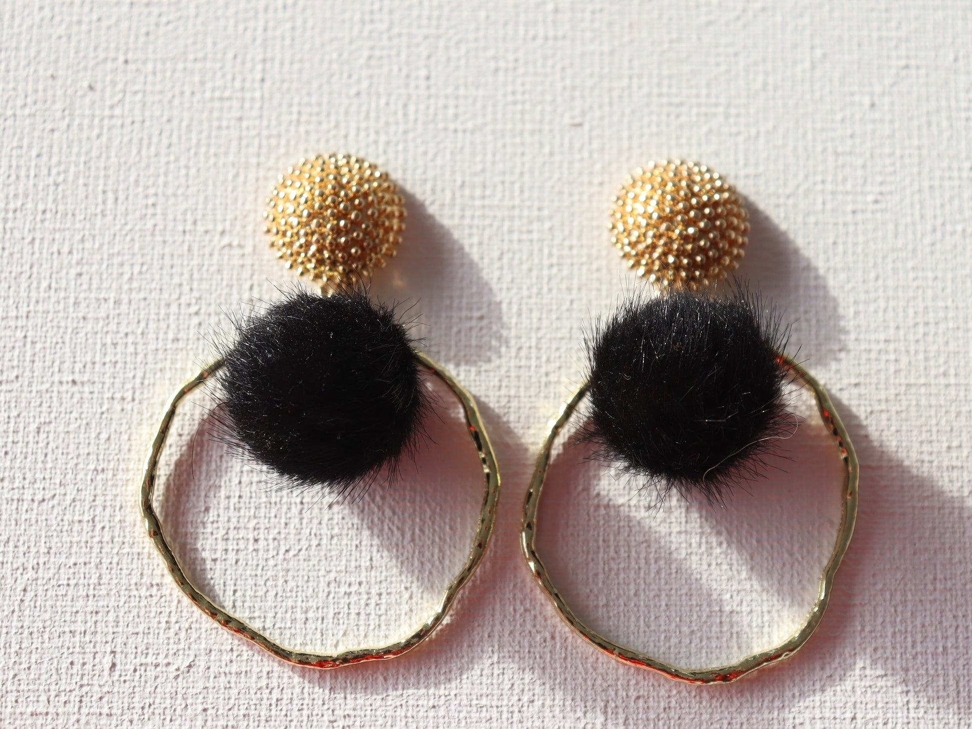 Goudkleurige ronde oorstekers met zwarte ponpom en goudkleurige ronde hanger
