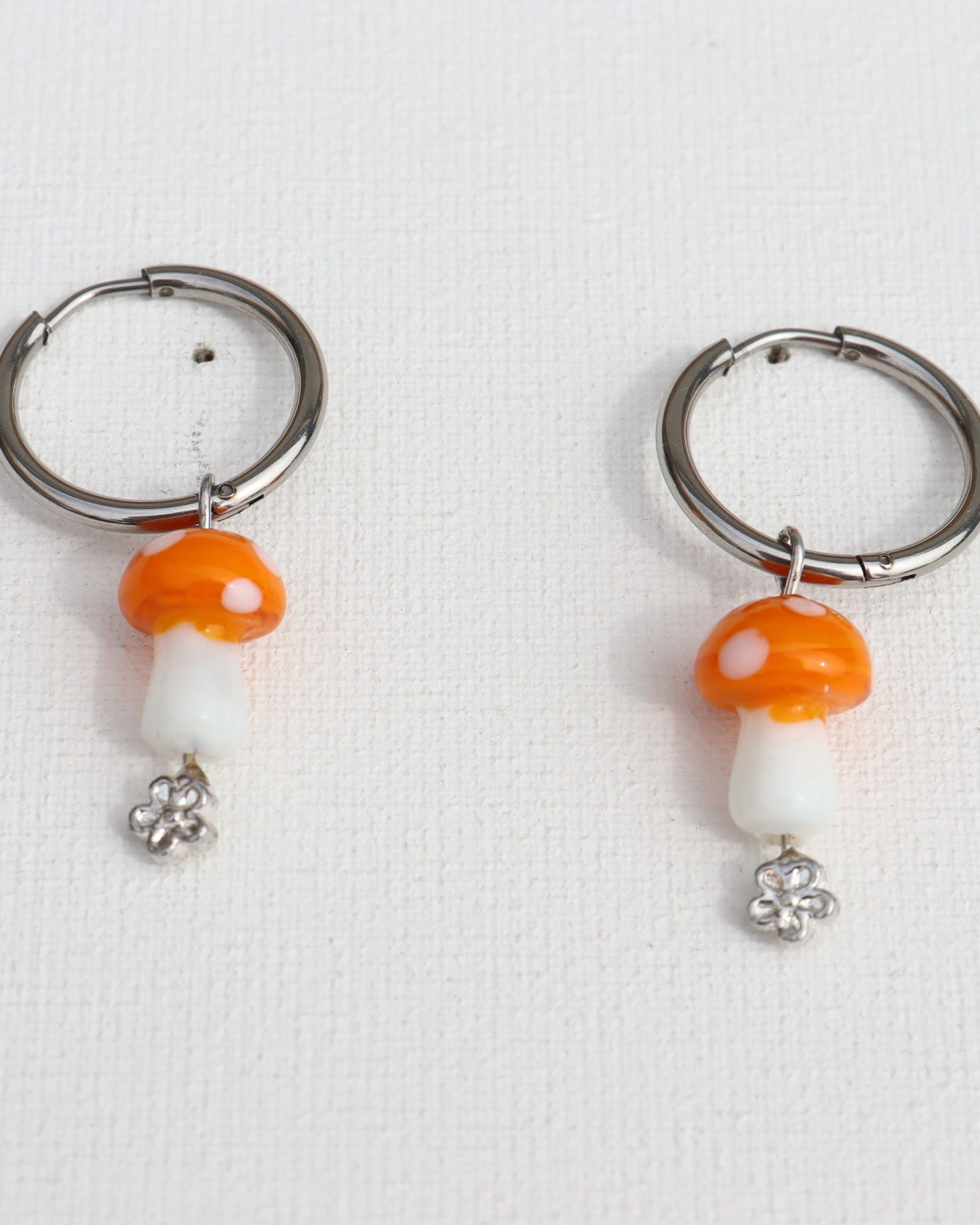 Zilverkleurige stainless steel creolen met oranje paddenstoel en bloemetje