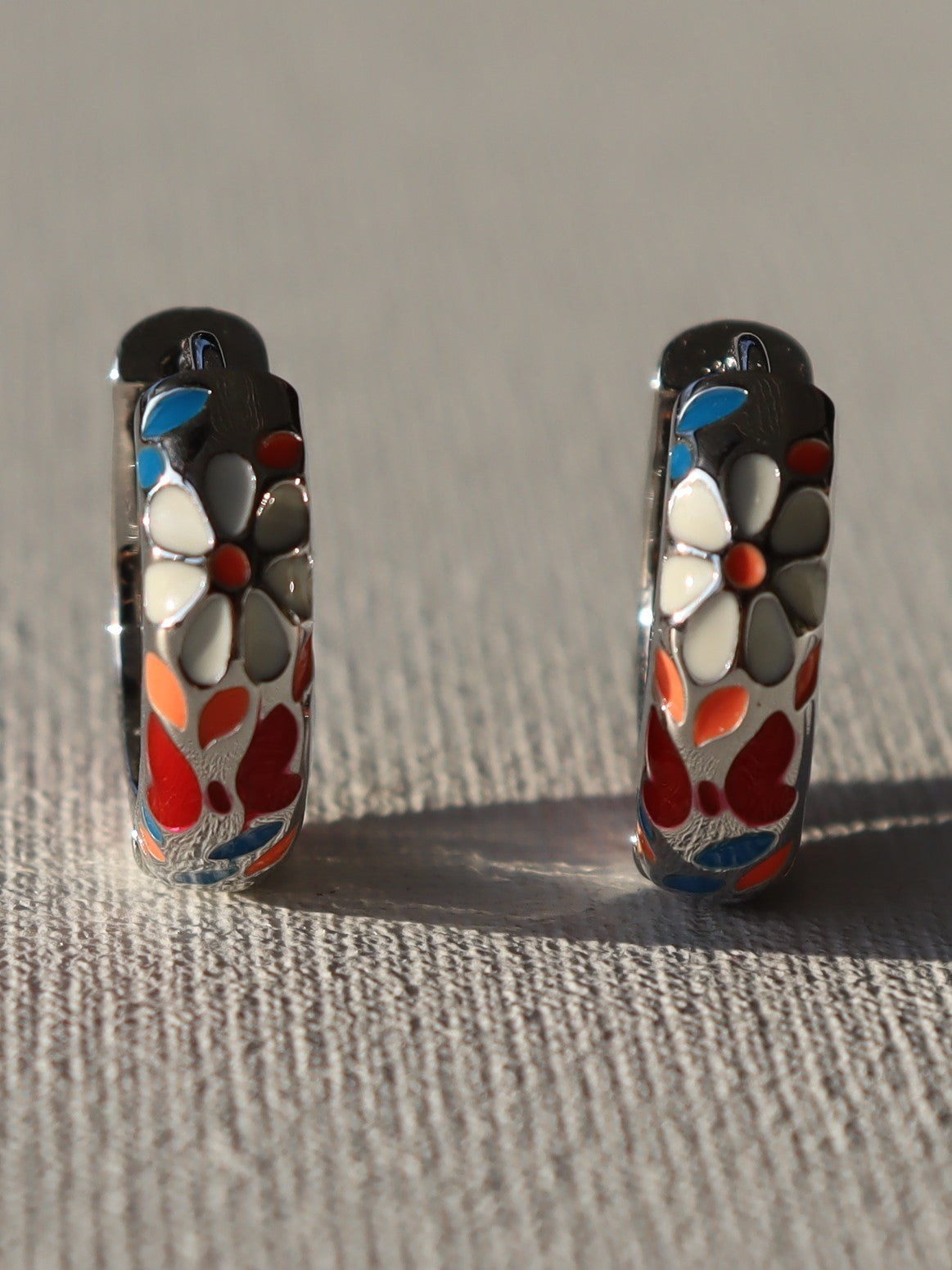 Zilverkleurige creolen metwitte bloemen en rode vlinder