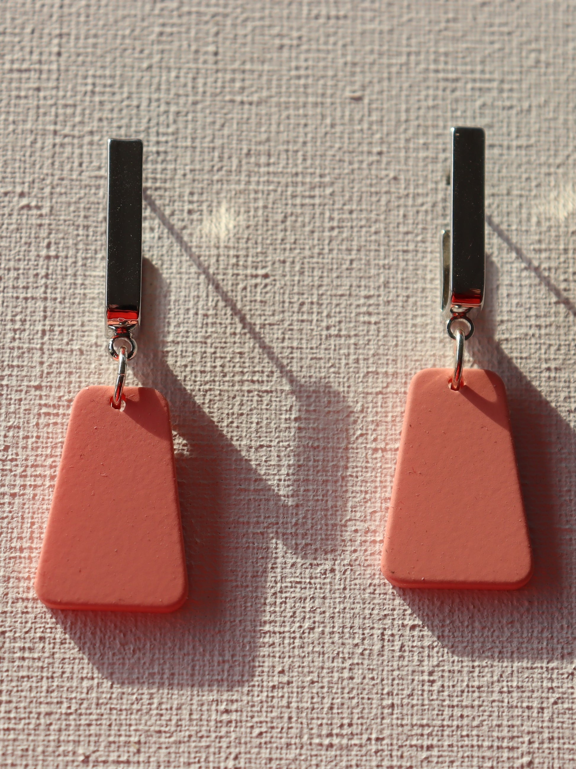 Zilverkleurige rechthoekige oorstekertjes met trapezium roze hanger