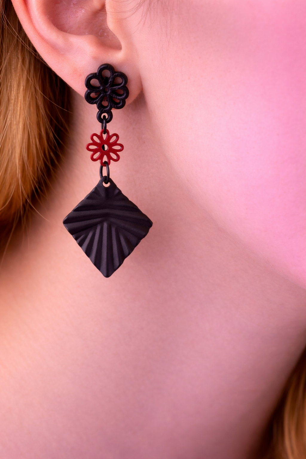 Zwarte bloem oorstekers met rood bloemetje en zwarte geribbelde ruit