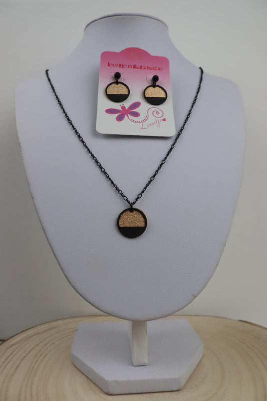 Zwarte ketting met goudkleurige ronde en zwarte halve cirkel en zwarte oorknopjes met goudkleurige ronde en zwarte halve cirkel