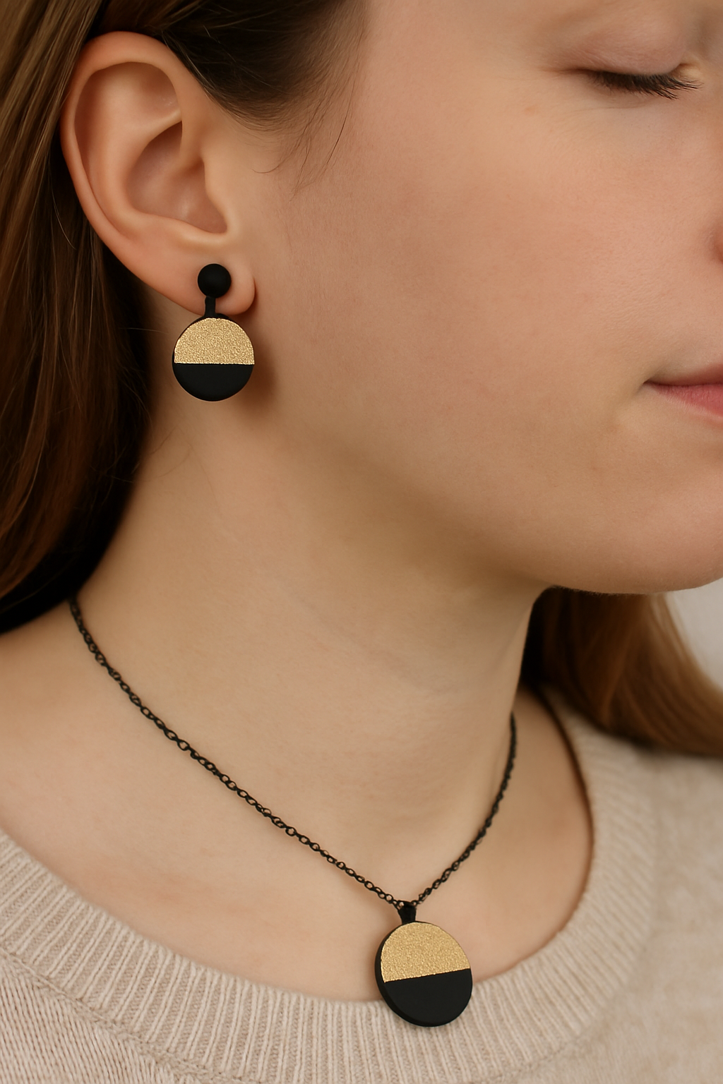 Zwarte_ketting_met_goudkleurige_ronde_en_zwarte_halve_cirkel_en_zwarte_oorknopjes_met_goudkleurige_ronde_en_zwarte_halve_cirkel