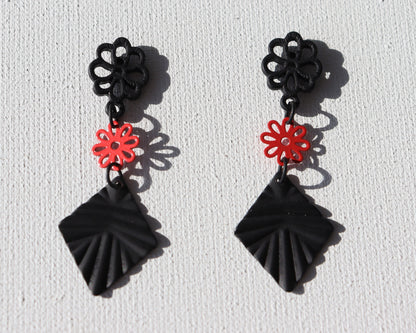 Zwarte bloem oorstekers met rood bloemetje en zwarte geribbelde ruit