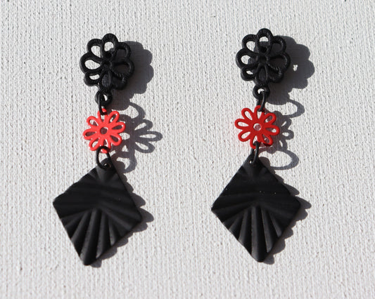Zwarte bloem oorstekers met rood bloemetje en zwarte geribbelde ruit