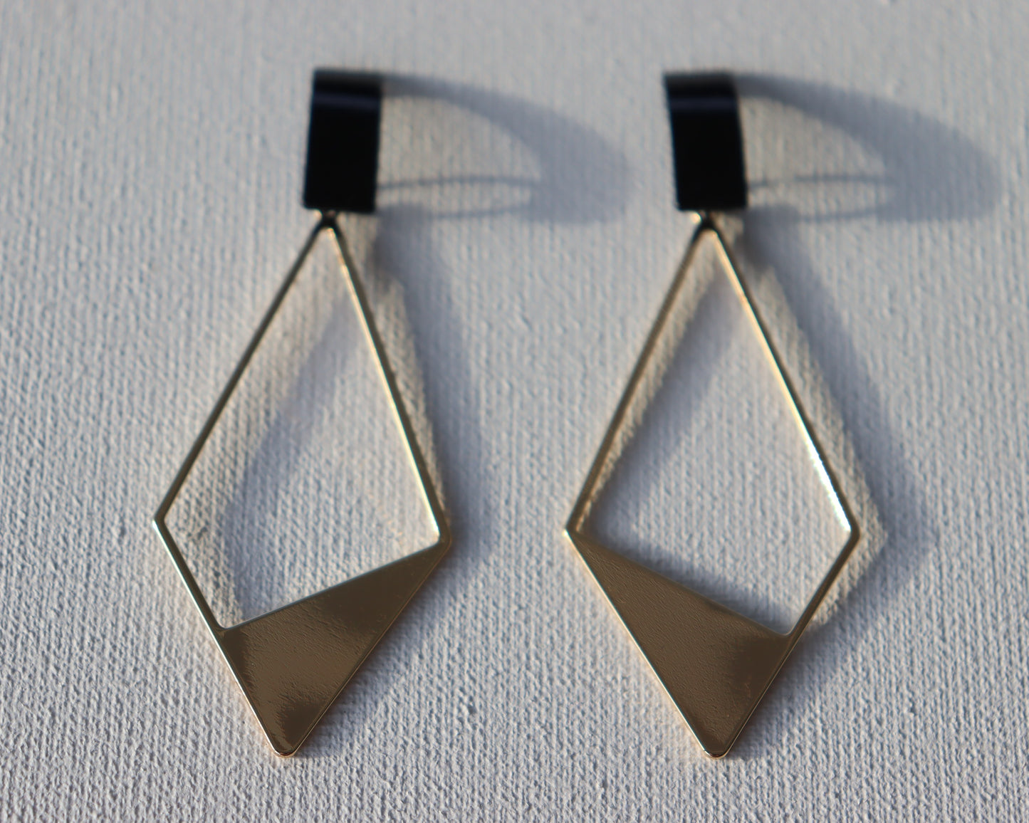 Zwarte rechthoekige oorstekers met goudkleurige half open ruit bedel