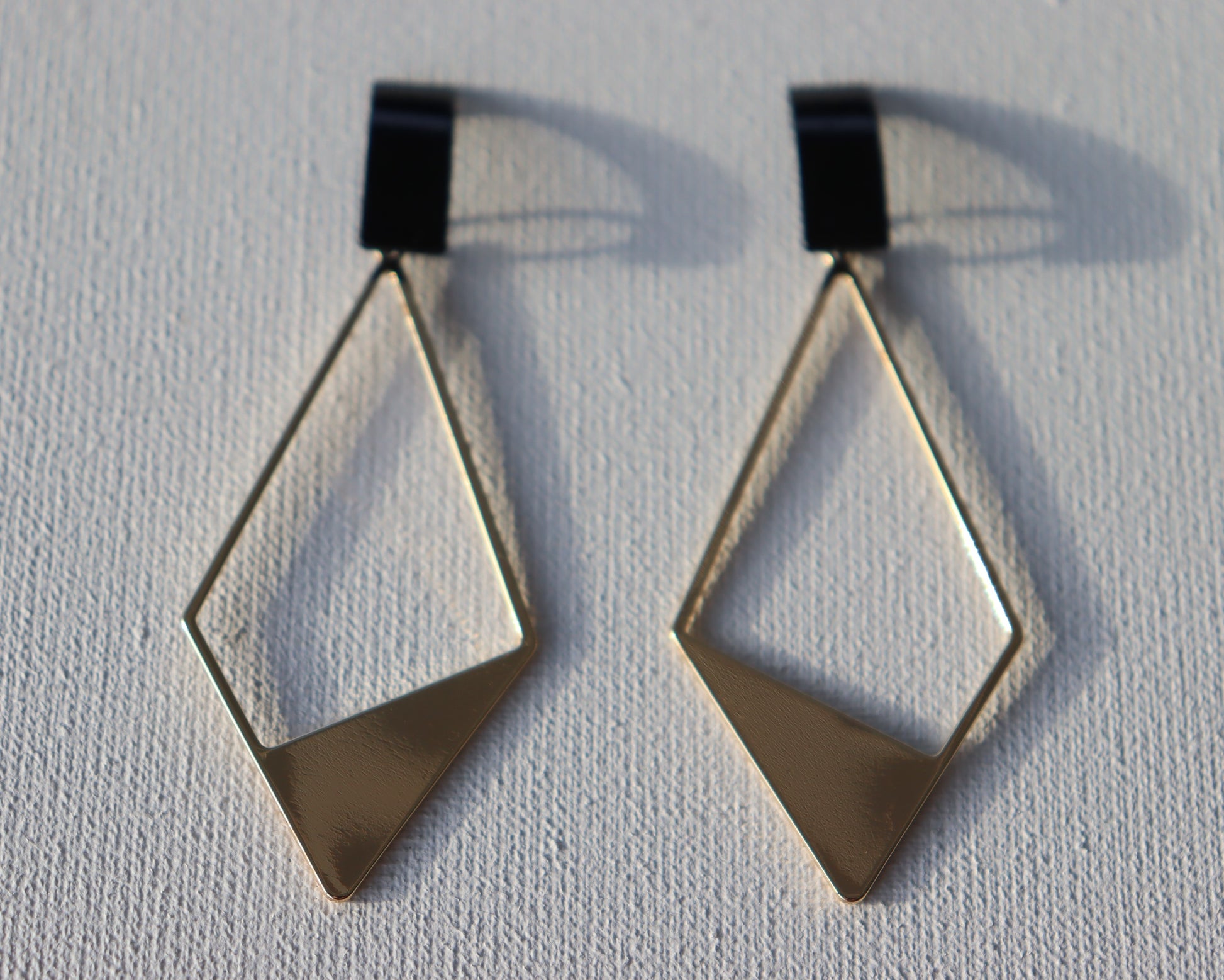 Zwarte rechthoekige oorstekers met goudkleurige half open ruit bedel