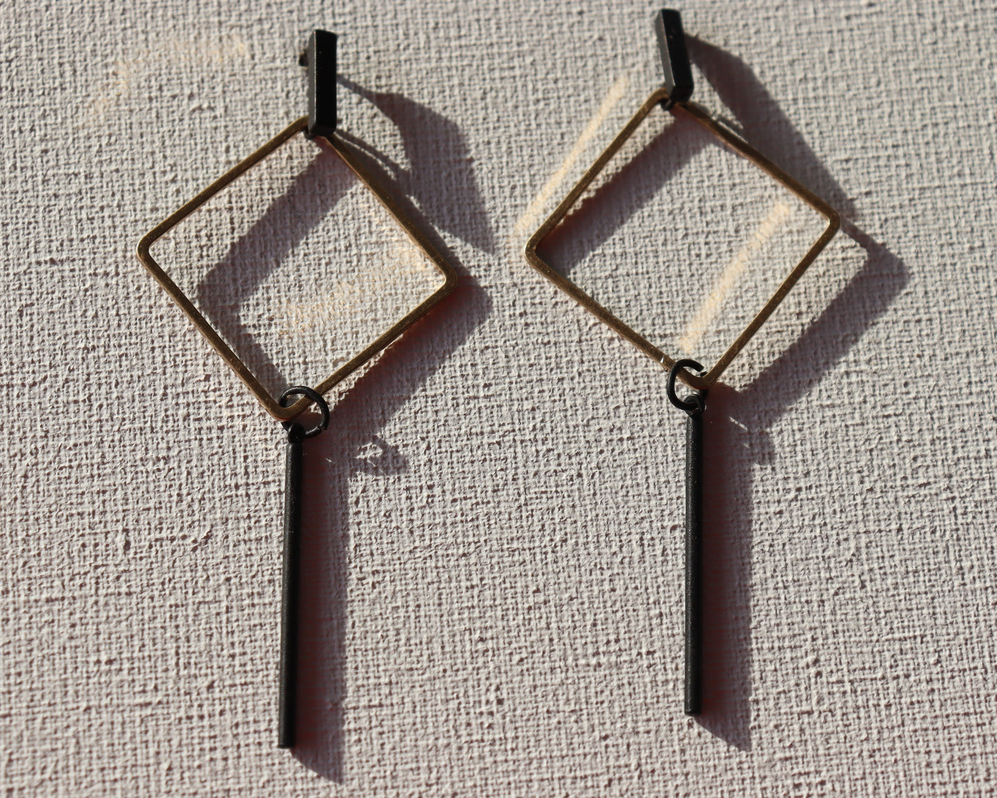 Zwarte staafjes met goudkleurige ruit hanger en zwarte staafjes