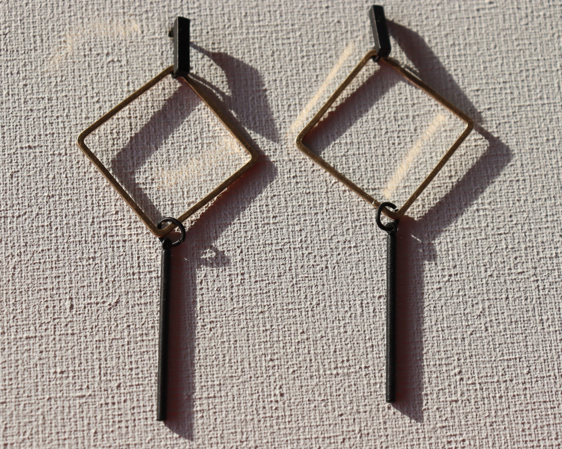 Zwarte staafjes met goudkleurige ruit hanger en zwarte staafjes